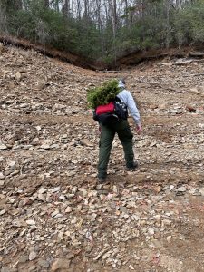 Man hiking with wreaths attached to back