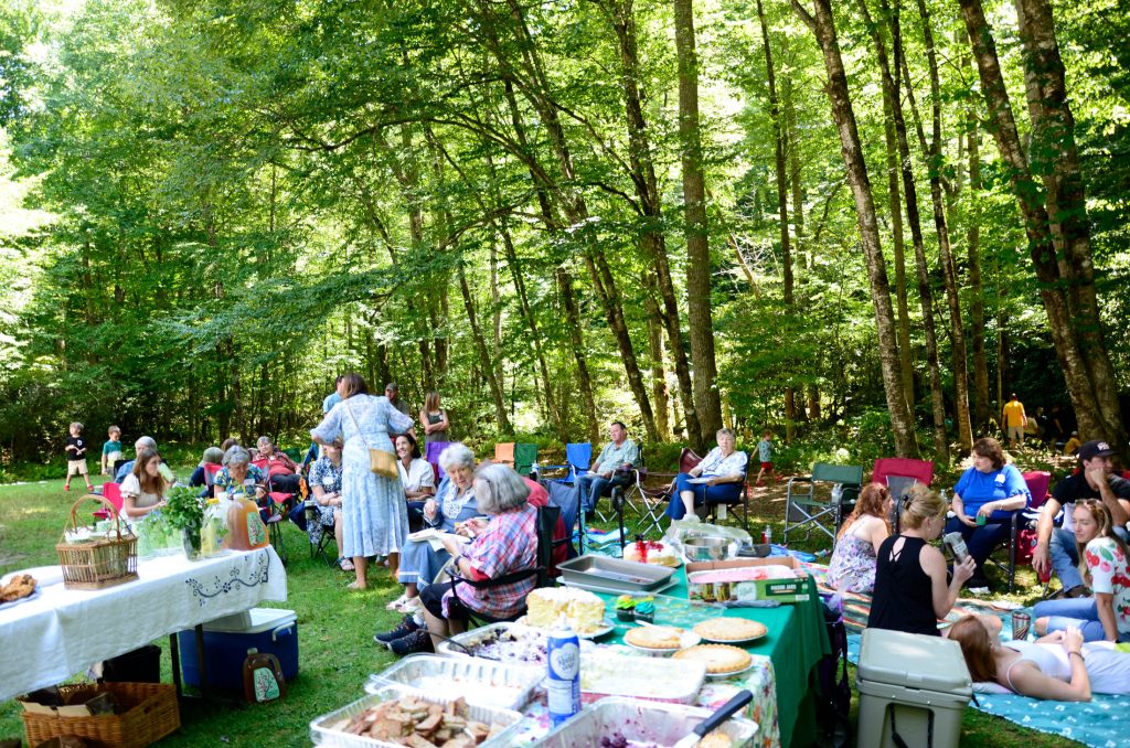 The tables are still full of food as reunion attendees spread out on the lawn to eat and enjoy each other’s company. Photo provided by Holly Kays, Smokies Life.