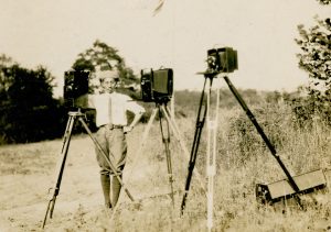 Photographer George Masa stands with two view cameras and a motion-picture camera on the grounds of the Biltmore Estate circa 1920s. Photo courtesy of Buncombe County Special Collections, Pack Memorial Public Library, Asheville, NC.